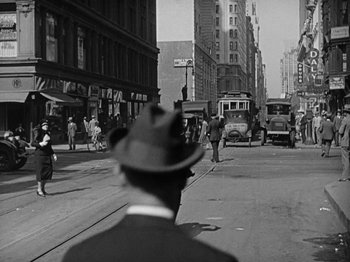 Movie still from “Speedy” (1928), directed by Ted Wilde – A man wearing a hat is walking down the street; Extreme Wide shot, Low angle