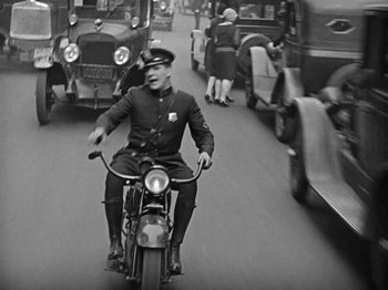 Movie still from “Speedy” (1928), directed by Ted Wilde – An old photo of a police officer on a motorcycle; Wide shot, High angle