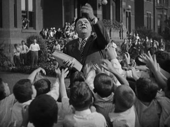 Movie still from “Speedy” (1928), directed by Ted Wilde – An old black and white photo of a man throwing a ball to a group of children; Medium shot, Low angle