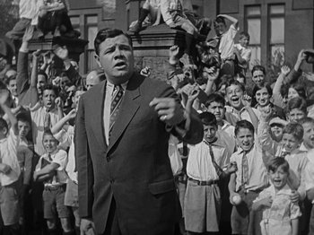 Movie still from “Speedy” (1928), directed by Ted Wilde – An old photo of a man in front of a group of people; Medium shot, Low angle