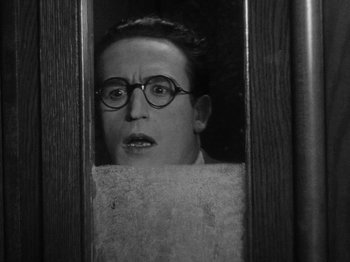 Movie still from “Speedy” (1928), directed by Ted Wilde – A man with glasses looking out of a window; Close Up shot, Low angle