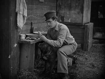 Movie still from “Speedy” (1928), directed by Ted Wilde – An old photo of a man sitting on a bench writing; Medium shot, High angle