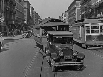 Movie still from “Speedy” (1928), directed by Ted Wilde – An old car is driving down the street; Wide shot, Low angle