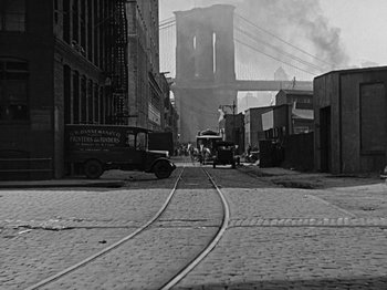 Movie still from “Speedy” (1928), directed by Ted Wilde – An old photo of a street with a bridge in the background; Wide shot, High angle