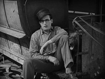 Movie still from “Speedy” (1928), directed by Ted Wilde – A man and his dog sitting on a chair; Medium shot, High angle