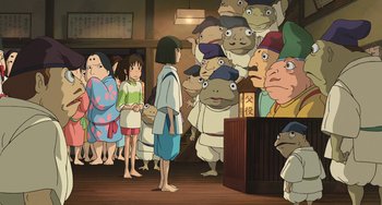 Movie still from “Spirited Away” (2001), directed by Hayao Miyazaki – A group of people standing in front of a crowd; Wide shot, High angle