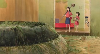 Movie still from “Spirited Away” (2001), directed by Hayao Miyazaki – Two girls are standing in front of a pile of hay; Wide shot, High angle