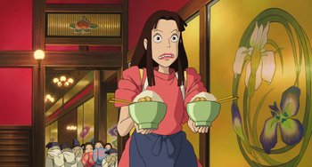 Movie still from “Spirited Away” (2001), directed by Hayao Miyazaki – An animated woman holding two bowls of food in her hands; Medium shot, Low angle