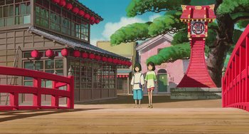 Movie still from “Spirited Away” (2001), directed by Hayao Miyazaki – Two women are walking on the sidewalk of an asian city; Extreme Wide shot, Low angle