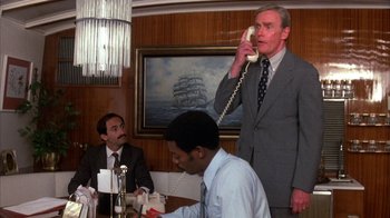 Movie still from “Spring Break” (1983), directed by Sean S. Cunningham – A man in a suit talking on a phone; Medium shot, Low angle