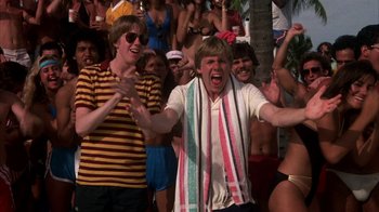Movie still from “Spring Break” (1983), directed by Sean S. Cunningham – A group of people that are standing in the grass; Medium shot, Low angle
