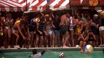Movie still from “Spring Break” (1983), directed by Sean S. Cunningham – A group of men standing next to each other in front of a swimming pool; Wide shot, High angle