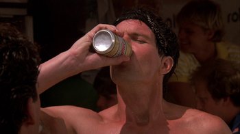 Movie still from “Spring Break” (1983), directed by Sean S. Cunningham – A shirtless man drinking a can of beer; Close Up shot, Low angle
