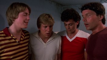 Movie still from “Spring Break” (1983), directed by Sean S. Cunningham – A group of young men standing next to each other in a room; Medium shot, Low angle