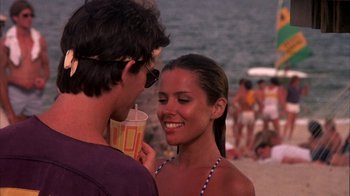 Movie still from “Spring Break” (1983), directed by Sean S. Cunningham – A man and a woman standing next to each other on the beach; Medium shot, Over the shoulder angle