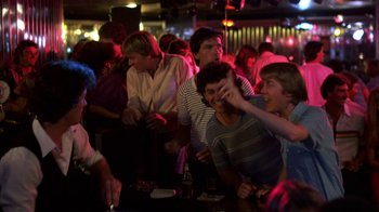 Movie still from “Spring Break” (1983), directed by Sean S. Cunningham – A group of people sitting at a bar drinking; Medium shot, Over the shoulder angle