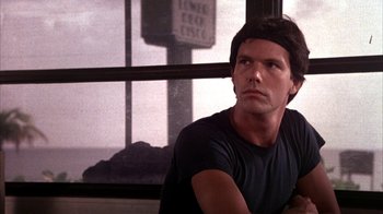 Movie still from “Spring Break” (1983), directed by Sean S. Cunningham – A man sitting in front of a large window; Close Up shot, Low angle