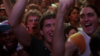 Movie still from “Spring Break” (1983), directed by Sean S. Cunningham – A group of people in a room watching a concert; Close Up shot, Low angle