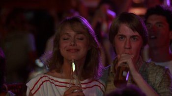 Movie still from “Spring Break” (1983), directed by Sean S. Cunningham – A woman holding a drink in her hand and a man holding a drink in his other hand; Medium shot, Low angle
