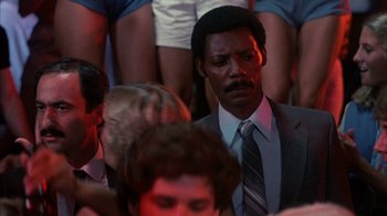 Movie still from “Spring Break” (1983), directed by Sean S. Cunningham – A man in a gray suit and a striped neck tie; Close Up shot, Over the shoulder angle