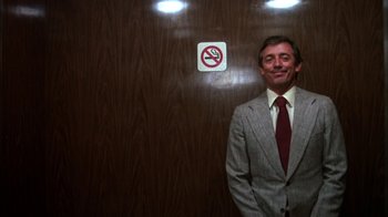 Movie still from “Spring Break” (1983), directed by Sean S. Cunningham – A man standing in front of a no smoking sign; Medium shot, Low angle