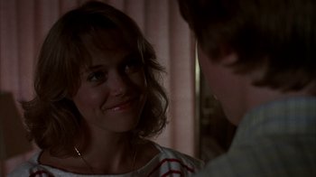 Movie still from “Spring Break” (1983), directed by Sean S. Cunningham – A woman smiles at the camera in front of a mirror; Close Up shot, Over the shoulder angle