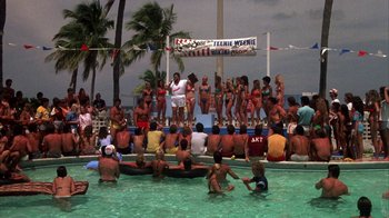 Movie still from “Spring Break” (1983), directed by Sean S. Cunningham – A group of people in a pool at a party; Extreme Wide shot, High angle