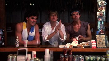 Movie still from “Spring Break” (1983), directed by Sean S. Cunningham – A group of people sitting at a bar; Medium shot, Low angle