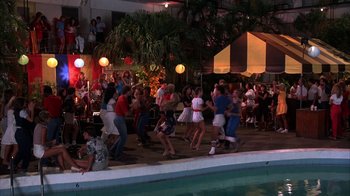 Movie still from “Spring Break” (1983), directed by Sean S. Cunningham – A group of people dancing next to a swimming pool; Wide shot, High angle