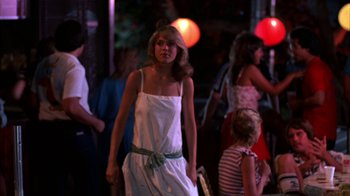 Movie still from “Spring Break” (1983), directed by Sean S. Cunningham – A woman in a white sundress walking down a street; Medium shot, Over the shoulder angle