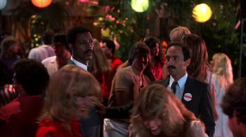 Movie still from “Spring Break” (1983), directed by Sean S. Cunningham – A group of people standing in front of a crowd; Medium shot, Over the shoulder angle