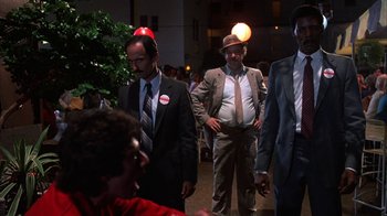 Movie still from “Spring Break” (1983), directed by Sean S. Cunningham – A group of men in suits and ties standing next to each other; Medium shot, Over the shoulder angle