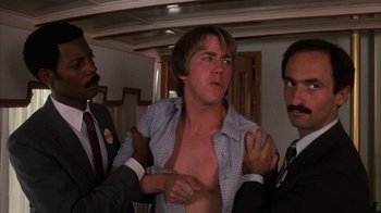 Movie still from “Spring Break” (1983), directed by Sean S. Cunningham – A man is being restrained by two other men; Medium shot, Over the shoulder angle