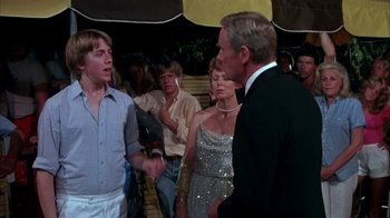 Movie still from “Spring Break” (1983), directed by Sean S. Cunningham – A group of people standing next to each other in a room; Medium shot, Over the shoulder angle