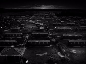Movie still from “Stalag 17” (1953), directed by Billy Wilder – A black and white photo of an industrial area; Extreme Wide shot, High angle