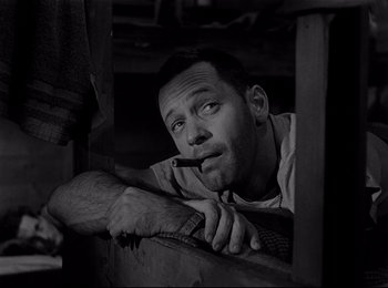 Movie still from “Stalag 17” (1953), directed by Billy Wilder – A black and white photo of a man smoking a cigarette; Close Up shot, Low angle