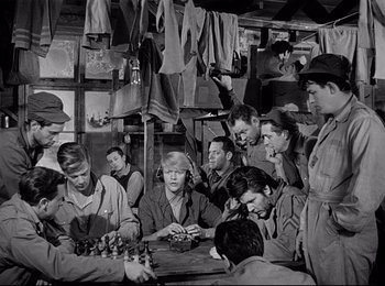 Movie still from “Stalag 17” (1953), directed by Billy Wilder – A group of men sitting around a table; Medium shot, High angle