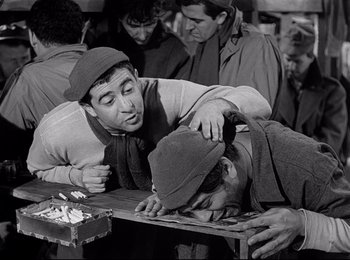Movie still from “Stalag 17” (1953), directed by Billy Wilder – A group of men standing next to each other on a table; Medium shot, Over the shoulder angle