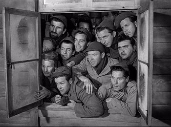 Movie still from “Stalag 17” (1953), directed by Billy Wilder – A group of men sitting together in a box; Medium shot, High angle