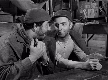 Movie still from “Stalag 17” (1953), directed by Billy Wilder – A couple of men sitting next to each other; Medium shot, Over the shoulder angle