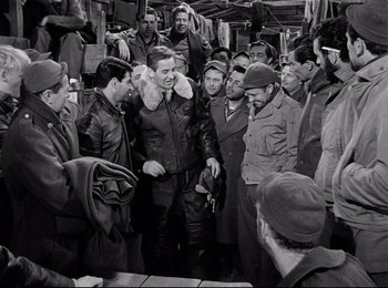 Movie still from “Stalag 17” (1953), directed by Billy Wilder – A group of men standing next to each other in a room; Medium shot, High angle