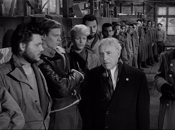 Movie still from “Stalag 17” (1953), directed by Billy Wilder – A group of men standing next to each other in a line; Medium shot, Low angle