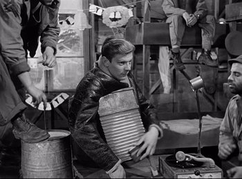Movie still from “Stalag 17” (1953), directed by Billy Wilder – A black and white photo of a man holding a barrel; Medium shot, Low angle