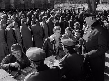 Movie still from “Stalag 17” (1953), directed by Billy Wilder – A group of men standing around a crowd of people; Medium shot, High angle