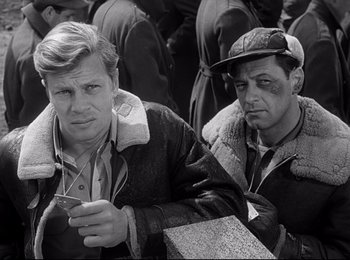 Movie still from “Stalag 17” (1953), directed by Billy Wilder – Two men sitting next to each other holding a cell phone; Medium shot, High angle