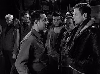 Movie still from “Stalag 17” (1953), directed by Billy Wilder – A black and white photo of a group of men; Medium shot, Over the shoulder angle