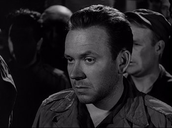 Movie still from “Stalag 17” (1953), directed by Billy Wilder – Black and white photograph of a man in a military uniform; Close Up shot, Over the shoulder angle