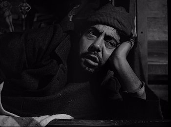 Movie still from “Stalag 17” (1953), directed by Billy Wilder – Black and white photograph of a man with a hat on; Close Up shot, High angle
