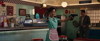 A woman holding a gun while standing in a kitchen
