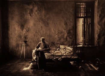 Movie still from “Stalker” (1979), directed by Andrei Tarkovsky – An old man sitting on a couch in a room; Wide shot, High angle